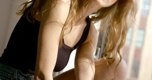 Charming Young Woman Is Smiling and Looking at Camera Playing with Her Light Brown Hair