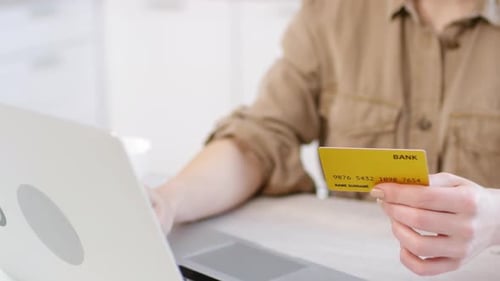 Adult Using Credit Card and Laptop at Home