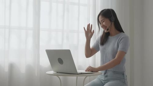 Smiling Woman Working Remotely on Laptop With Headset