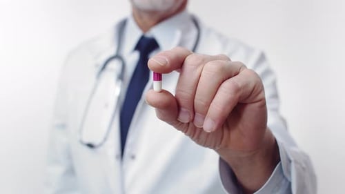 Doctor Holding Pink and White Capsule Pill Close Up