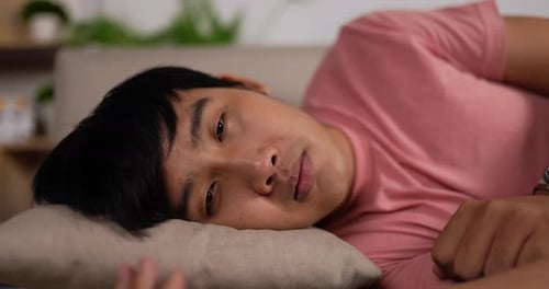 Asian young man napping on sofa at home