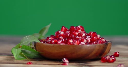 Pomegranate Seeds in Bowl with Green Background