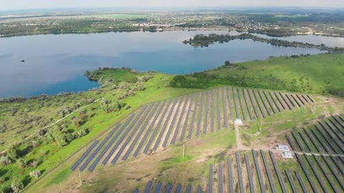 Luftaufnahme des Solarkraftwerks im grünen Feld in der Nähe des Flusses bei sonnigem Tag