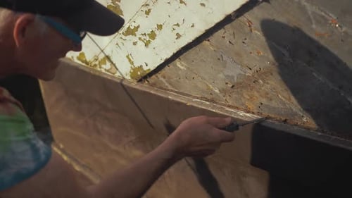 Adult male repairing weathered boat surface