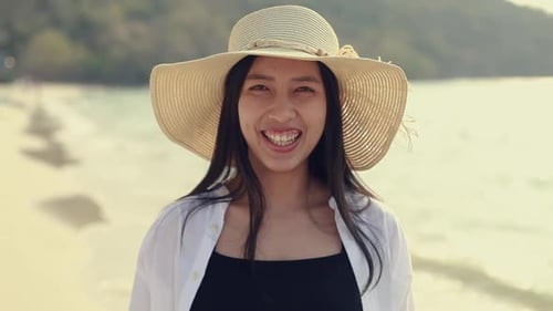 Asian woman traveler smiling while standing on the beach enjoying the summer weekend.