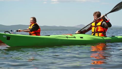 Couple kayaking together on calm water on summer day