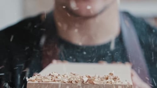 Carpentry Works Worker Blows Off the Wood Shavings From a Detail