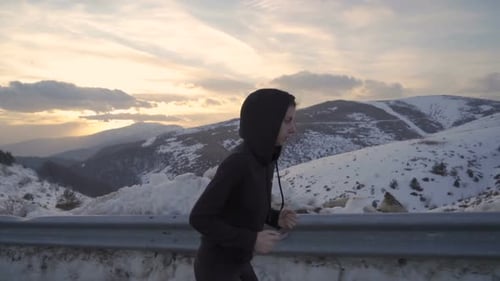 Woman Running in Snowy Mountains at Sunrise