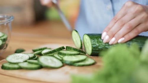 Close Up Female Hands Cutting Cucumber on Wooden Slicing Board