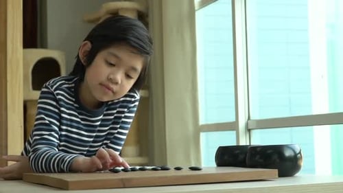 Un joli garçon asiatique a appris à jouer au jeu de go chinois tout seul