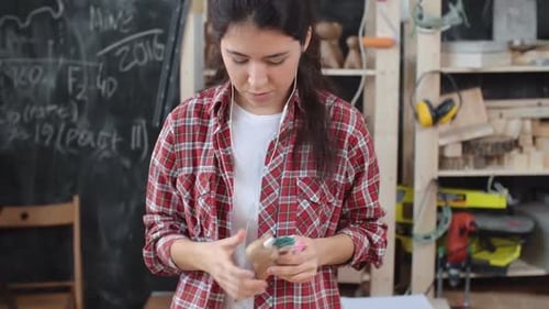 Woman Painting Wooden Figure in Workshop