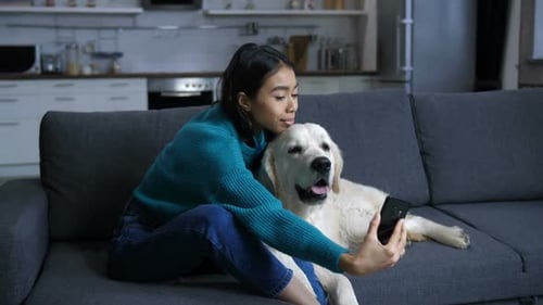 Woman Takes Selfie with Golden Retriever on Couch