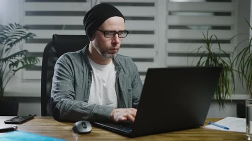 An Adult Experienced Man Works at a Laptop