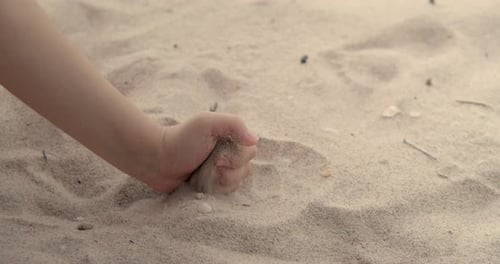 Closeup Child Girl Pouring Sand Going Through Fingers Slow Motion on the Beach with Sun Flare and