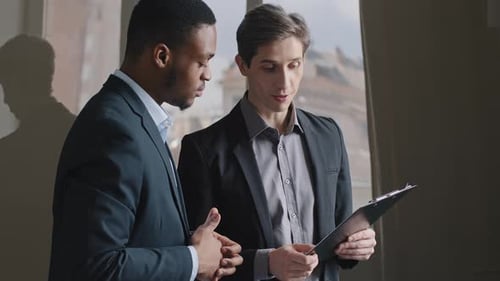 Businessmen Discussing a Report in Modern Office