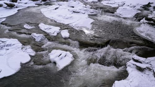 Mountain Stream in Winter. Mountain River Flowing Over Ice and Snow Near Rocks in Winter Landscape