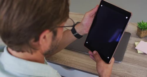 Caucasian male teacher having a videocall on digital tablet in the classroom at school