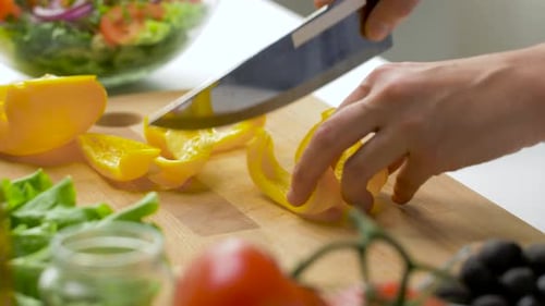 Hands Slicing Bell Pepper for Salad Preparation