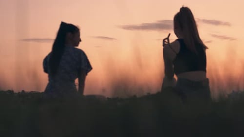 Two Women Chatting in a Field at Sunset