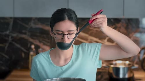 Young Woman with Spoon in Modern Kitchen