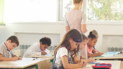 Children Writing at Desks in Bright Classroom