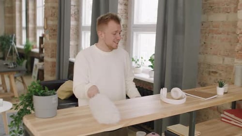 Enthusiastic Man Dancing While Cleaning His Apartment