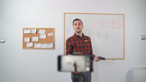 Young Teacher Teaching Remotely Using Smartphone Camera To Stream Lesson