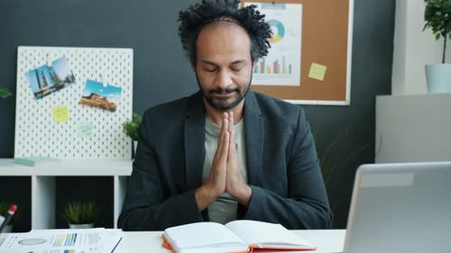 Man meditates at a desk in quiet office