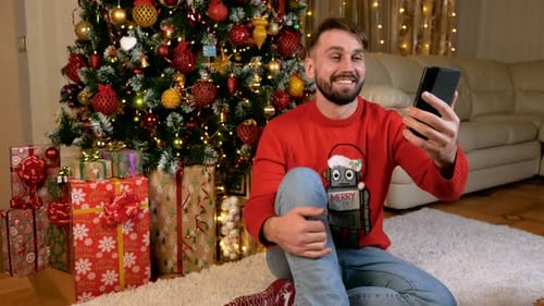 Man Video-Chatting by Christmas Tree in Cozy Home