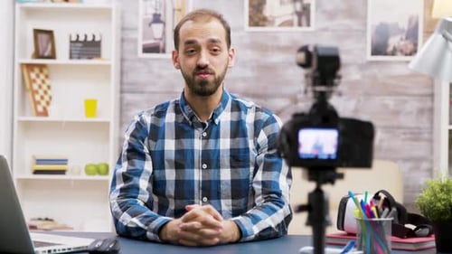 Man Vlogging and Speaking to a Camera at Desk