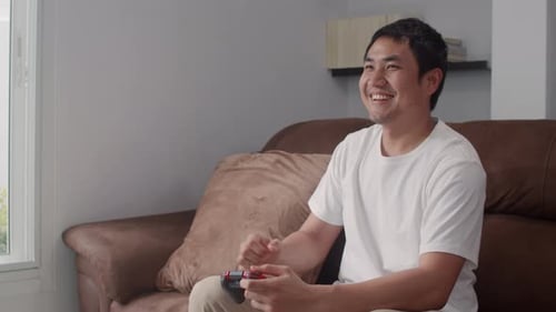 Man Playing Handheld Video Game on Couch Indoors