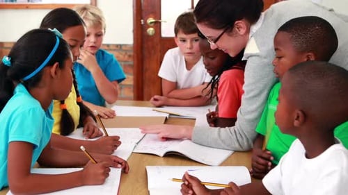 Teacher Helping Children with School Work in Classroom
