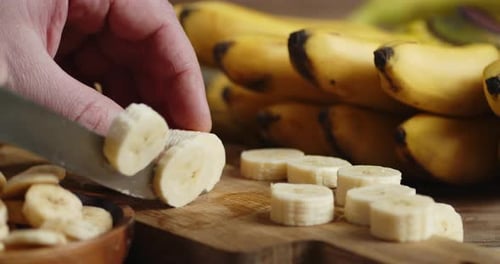 Slicing Yellow Bananas on Wooden Cutting Board