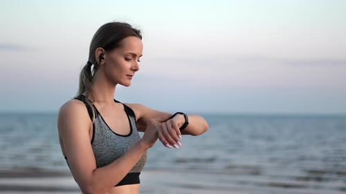 Woman Runner Heart Rate Monitoring Checking Smartwatch Data Sport Digital Accessory at Sunset Beach