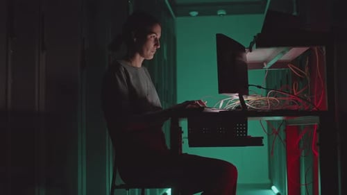 Woman Working on Computer in Dark Server Room