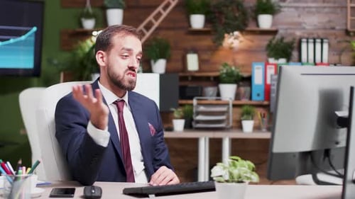 Man Talking at Desk With Hand Gestures