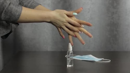 Woman sanitizes hands with sanitizer spray