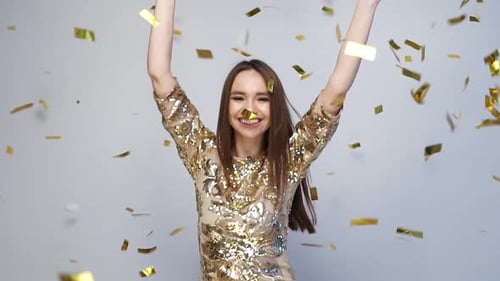 Happy Young Woman Dancing in Gold Confetti