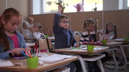 Enthusiastic Young Students in Classroom Raising Hands
