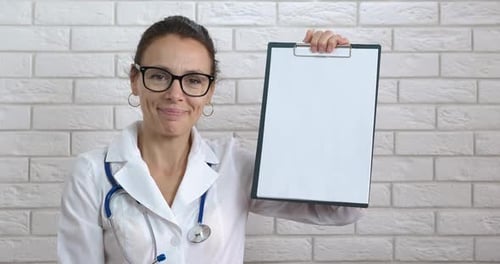 Woman Doctor Writing on Clipboard and Holding Up