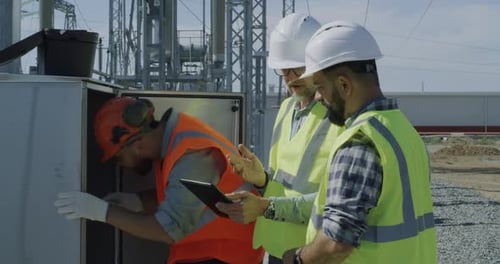 Construction Workers Inspecting Electrical Equipment with Tablet