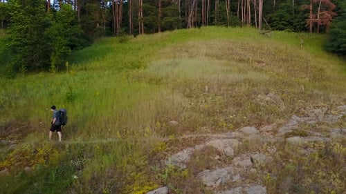 Hiker with Backpack Travels Through Rural Landscape