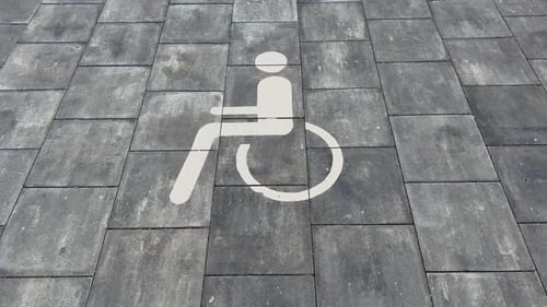Large Disabled Parking Lot White Sign Over Brick Pavement
