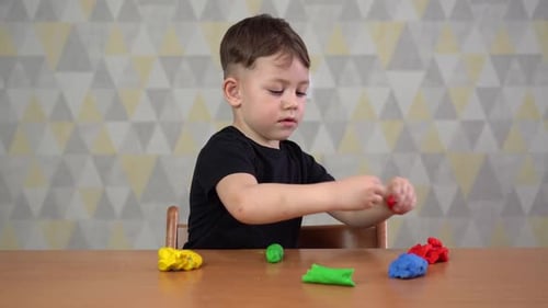 Focused Young Boy Playing with Modeling Clay Indoors