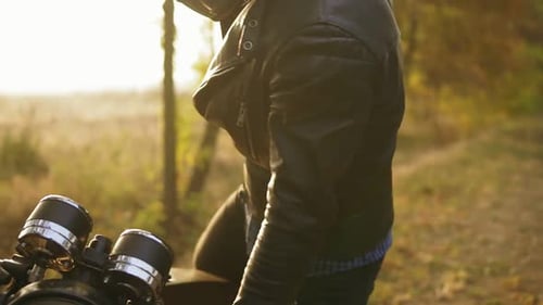 Back View of a Man in Helmet and Leather Jacket Coming Up to His Bike and Starting the Engine While