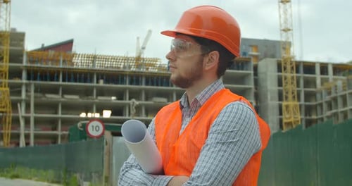 Portrait of an Architect or Builder in Hard Hat Standing in Front of Building Under Construction