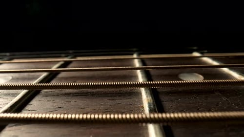 Slider Macro Shot eines Akustikgitarrenhalses mit Metallsaiten und Bünden auf schwarzem Hintergrund