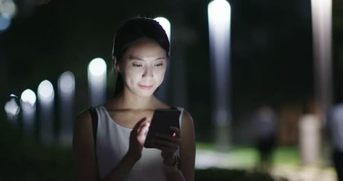 Woman use of mobile phone in city at night