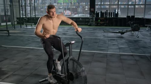 Man Works Out on Air Bike in Modern Gym