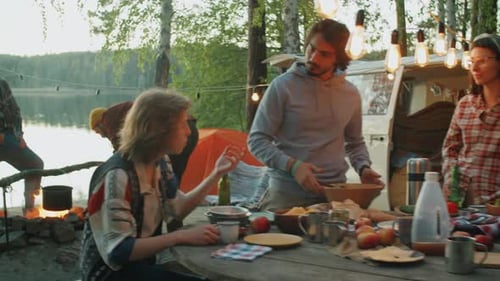 Friends Gather Around Campfire Near Lake